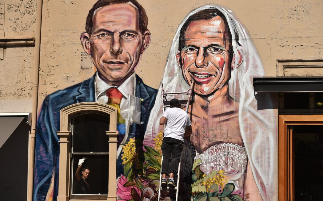 Australian street artist Scottie Marsh paints a mural of former Australian prime minister Tony Abbott wedding himself in Sydney after Mr Abbott urged Australians to "protect the family" with their vote in the same-sex marriage postal survey.