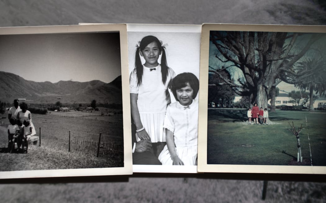 Joyce Harris (pictured center left) with her twin sister Toni (center right) as children, the photograph sits center of from, laid down next to old family photos from their childhood.