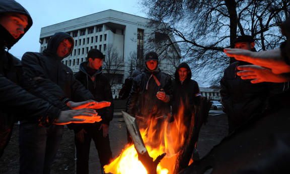 Pro-Russian demonstrators warm themselves near a bonfire as they rally near Crimean parliament building.