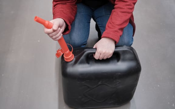Woman in the parking lot store chooses for buys a canister with a flexible hose under fuel.