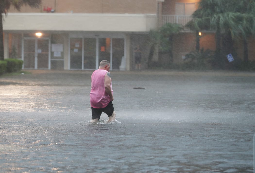 A man walks though a flooded parking lot as the outer bands of Hurricane Sally come ashore in Gulf Shores, Alambama, on 15 September 2020.