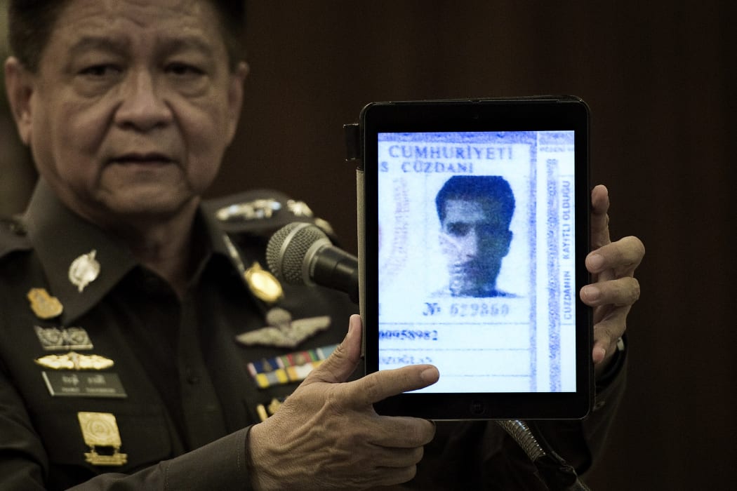 Thailand's national police spokesman Prawut Thavornsiri holds a tablet displaying a picture of Ahmet Bozaglan, a foreign man wanted by the police.