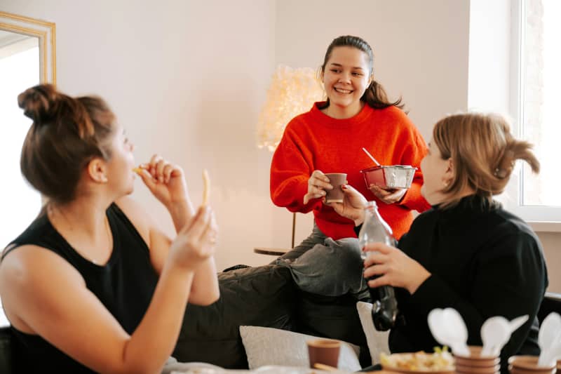 A group of friends gathered in a lounge, sharing food and drink.