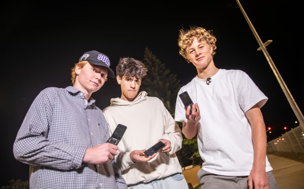 Teens Connor Cummins, Israel Cameron and Isaac Reid hold their brick phones.