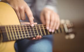 Teacher giving guitar lessons to pupil in a classroom