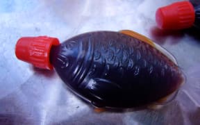 A plastic fish-shaped container of soy sauce.