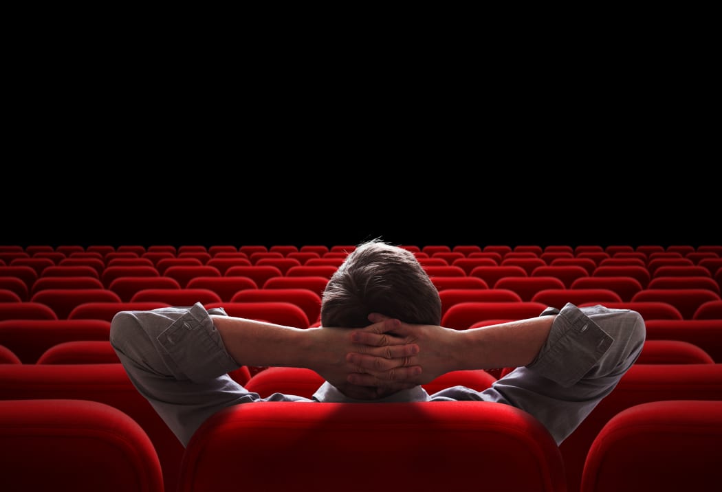 Image of happy male friends sitting in cinema watch film eating popcorn