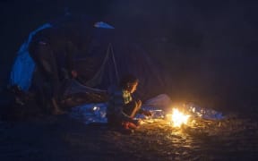 A child warms herself at makeshift camp on the Macedonian-Serbian border..