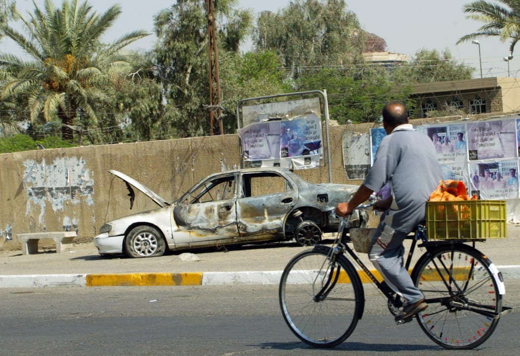 A cyclist passing by a burnt-out car a few days after Blackwater guards escorting US embassy officials opened fire in the Baghdad neighbourhood on 16 September 2007.