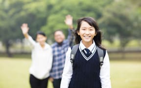 A photo of a cute young student girl with parent in school