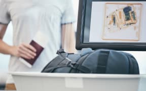 Airport security check. Young man holding passport and waiting for x-ray control his luggage.