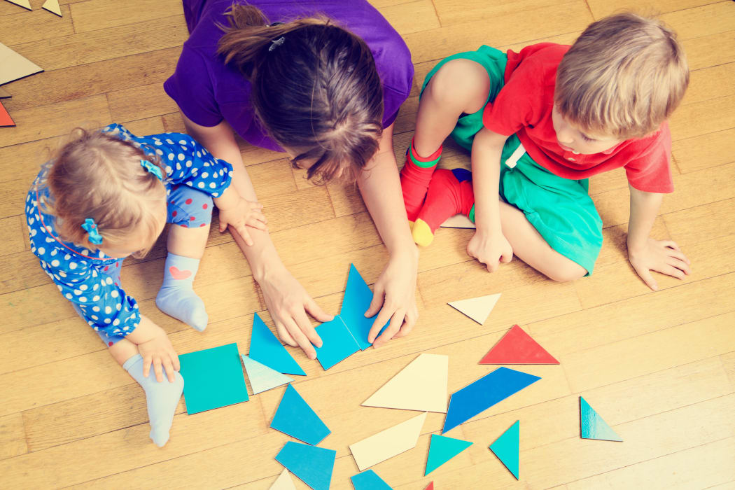 teacher and kids playing with geometric shapes, early learning