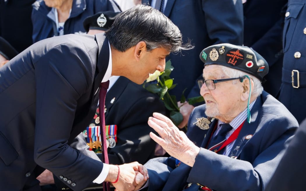 Britain's Prime Minister Rishi Sunak (L) meets with a British D-Day veteran during the UK Ministry of Defence and the Royal British Legion’s commemorative ceremony marking the 80th anniversary of the World War II "D-Day" Allied landings in Normandy, at the World War II British Normandy Memorial near the village of Ver-sur-Mer which overlooks Gold Beach and Juno Beach in northwestern France, on June 6, 2024. The D-Day ceremonies on June 6 this year mark the 80th anniversary since the launch of 'Operation Overlord', a vast military operation by Allied forces in Normandy, which turned the tide of World War II, eventually leading to the liberation of occupied France and the end of the war against Nazi Germany. (Photo by Ludovic MARIN / POOL / AFP)