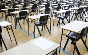 View of large exam room hall and examination desks tables lined up in rows ready for students at a high school to come and sit their exams tests papers.