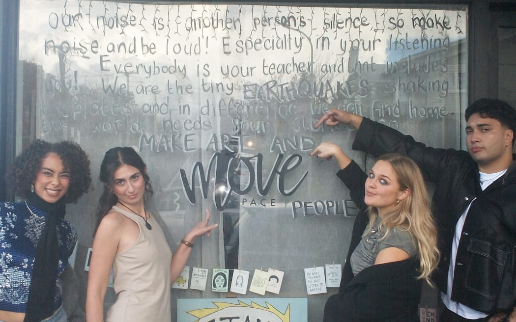 The cast pointing out window art that says 'make art and move'