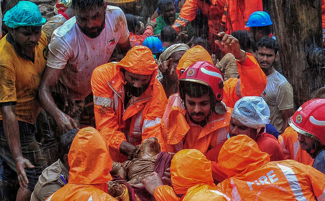 Rescue workers carry a body of a victim at a site of a landslide claimed to be caused by heavy rains in Kokkayar in India's Kerala state on October 17, 2021.