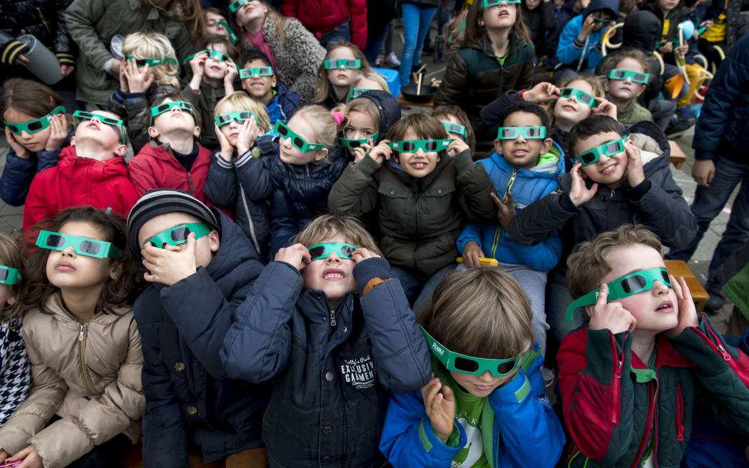 School children wear protective eye gear to watch a partial solar eclipse from their school yard in Amsterdam.