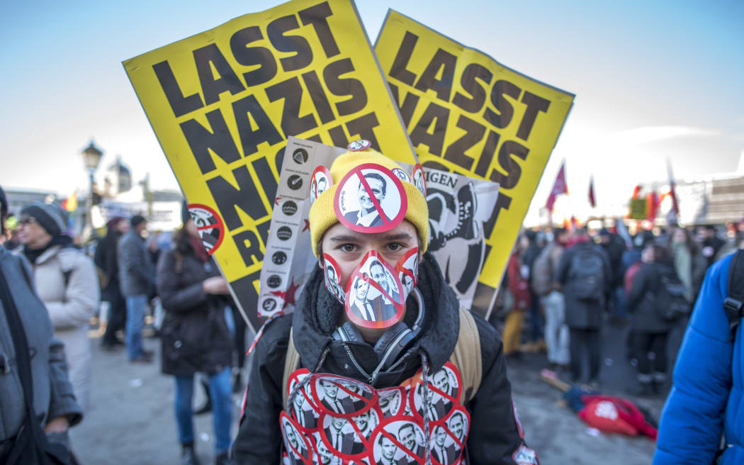 A protester stands with stickers depicting crossed out incoming vice-chancellor  of the far-right Freedom Party Christian Strache and incoming Austrian Chancellor of the conservative People's Party Sebastian Kurz.