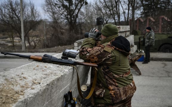 An Ukrainian serviceman looks through binoculars towards the town of Stoyanka at a checkpoint before the last bridge on the road that connects Stoyanka with Kyiv, on 6 March, 2022.