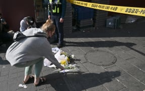 A woman lays a flower at the scene of a Halloween stampede in the capital's popular Itaewon district in Seoul on October 30, 2022. - More than 150 people were killed and scores more injured in a stampede at a packed Halloween event in central Seoul late on October 29, officials said, in one of South Korea's worst peacetime accidents. (Photo by Jung Yeon-je / AFP)