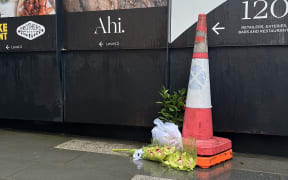Flowers laid outside the barriers of an Auckland construction site, on 21 July 2023, the day after the fatal shootings.