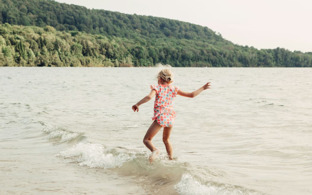 Child playing in water on beach.