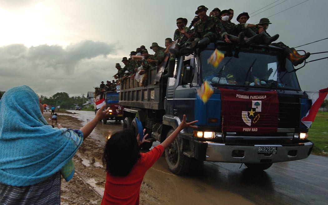 Indonesian refugees ask Indonesian soldiers for food as they pass by their refugee camp in Banda Aceh, 11 January 2005.