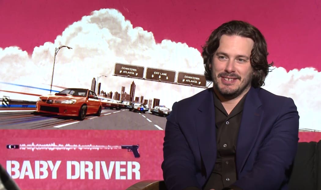 Edgar Wright in front of Baby Driver artwork