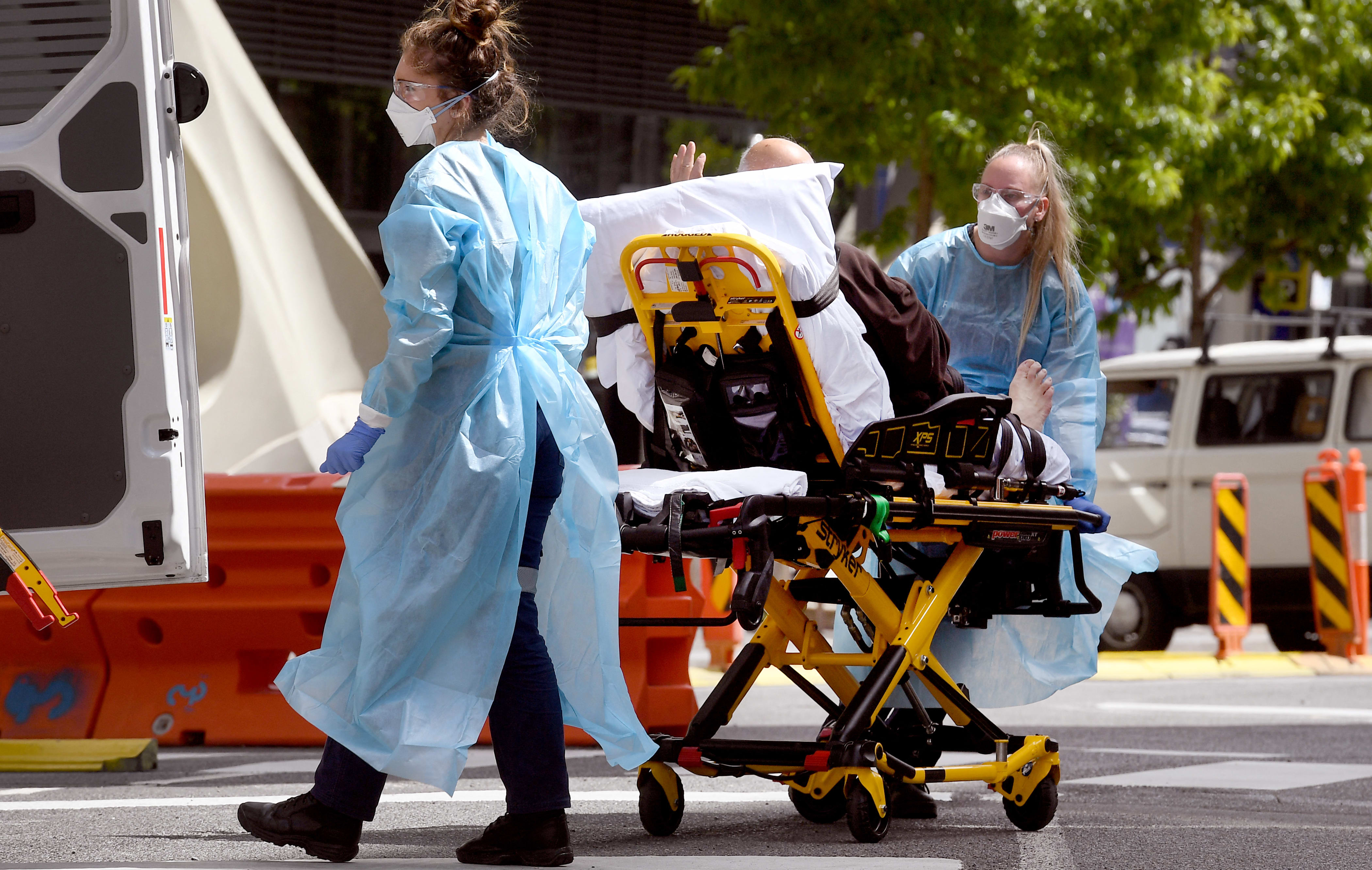 Medical staff stretchering a patient at Royal Melbourne Hospital. The state's surge in infection numbers has put pressure on the state's health system.
