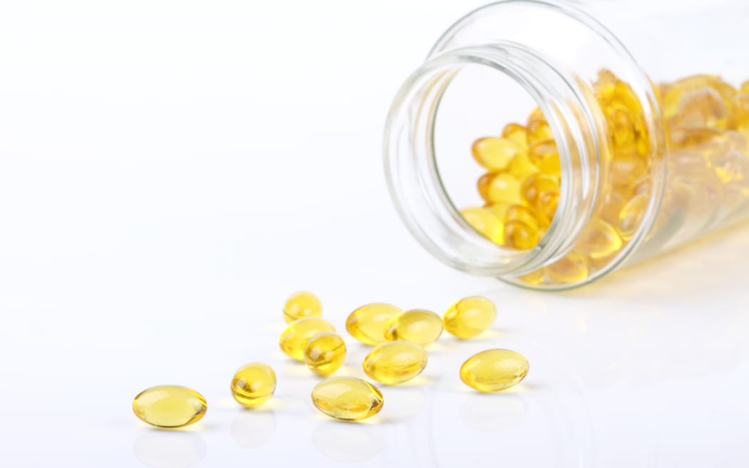 Macro view of vitamin D capsules on white with bottle in background