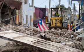 A Puerto Rican flag waves on top of a pile of rubble as debris is removed from a main road in Guanica, Puerto Rico on January 8, 2020, one day after the earthquake.