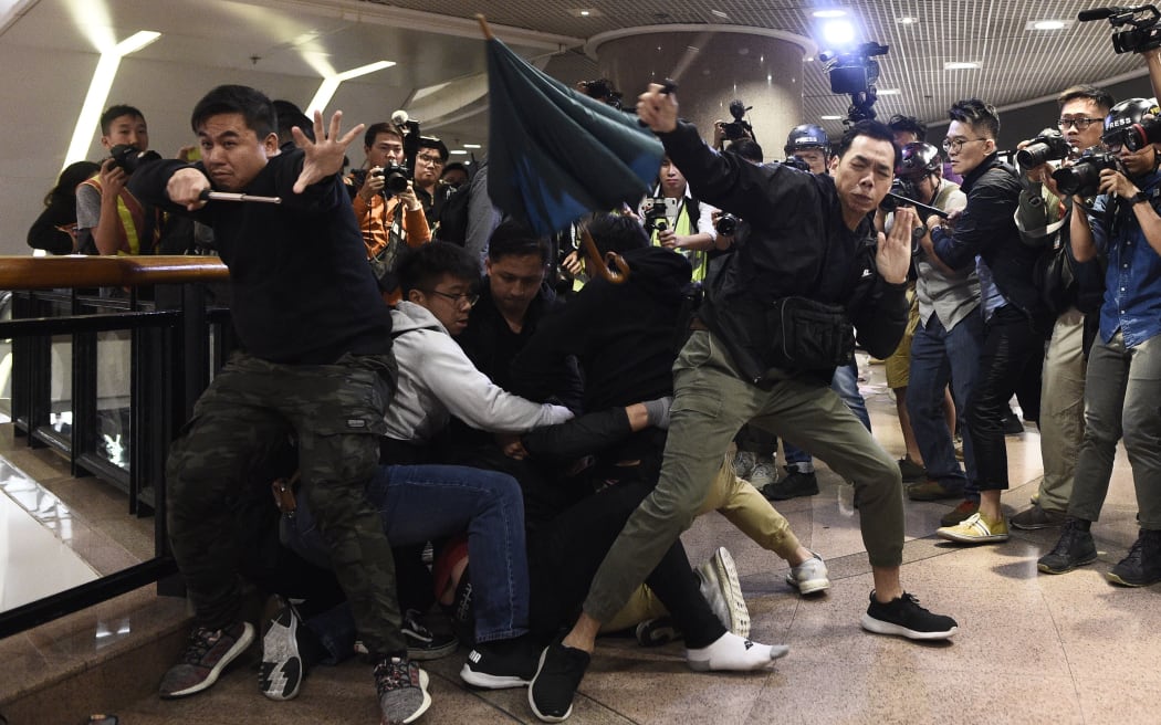 Police react as anti-government protesters throw an umbrella at them after a protester was detained in a shopping mall in the Tsim Sha Tsui district of Hong Kong on December 24, 2019.