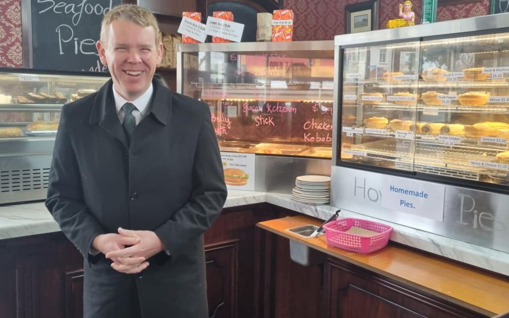 Chris Hipkins stands next to a cabinet of pies and sausage rolls.