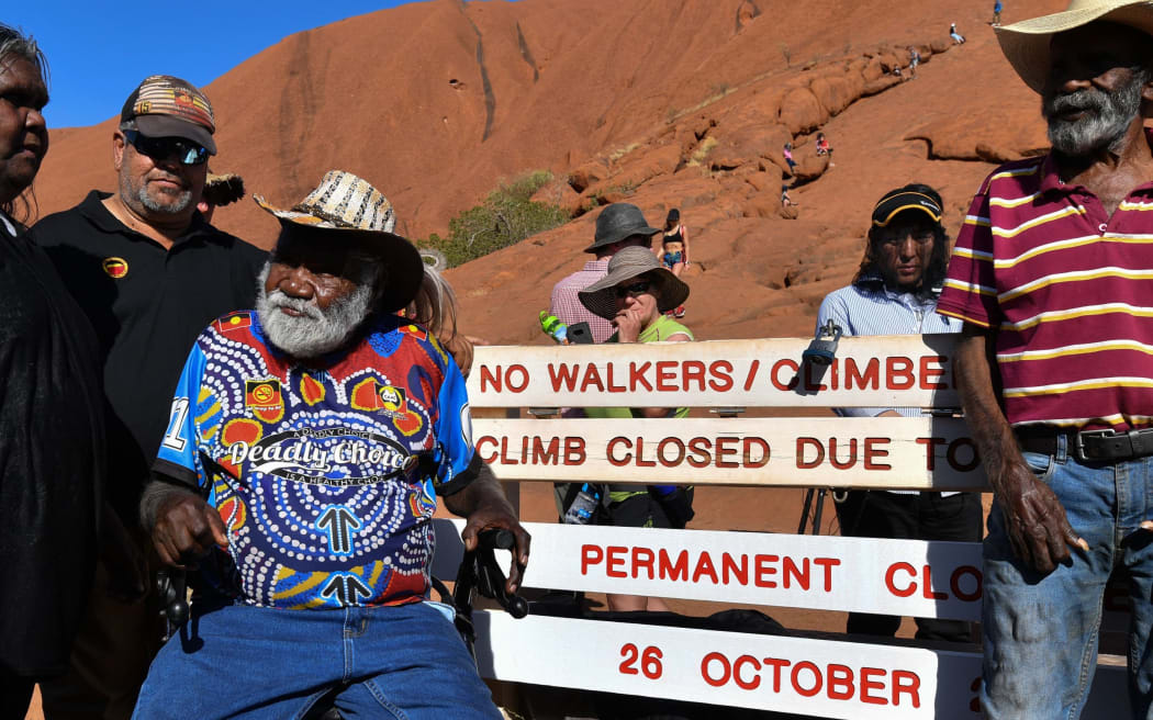 Aboriginal elders stand beside new signage at the base of Uluru, also known as Ayers Rock, ahead of the day's end marking the start of a permanent ban on climbing the monolith, at Uluru-Kata Tjuta National Park in Australia's Northern Territory on October 25, 2019.