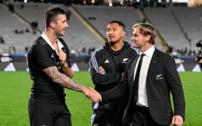 All Blacks coach Scott Robertson (R) shakes hands with lock Josh Lord while Samipeni Finau looks on.