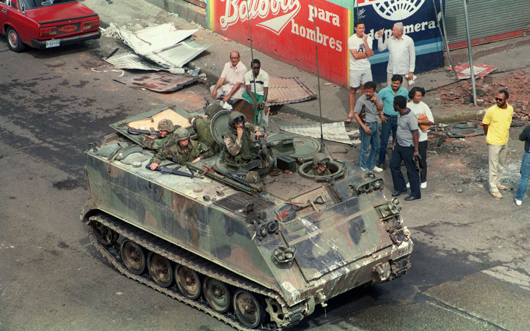 US troops patrol the streets and clear debris in the area of the Panamanian Defense Force headquarters in Panama City during Operation Just Cause, on December 26, 1989. On December 20, 1989, The US army invaded the country to remove Panama's General Manuel Antonio Noriega from power and bring him to the US for trial on drug charges. (Photo by MANOOCHER DEGHATI / AFP)