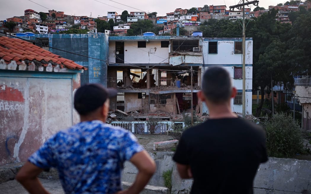 Jesus Linares, 48, stands next to a local resident as he looks at his damaged apartment building, after the US launched a strike on Venezuela over the weekend.
Mandatory Credit:	Gaby Oraa/Reuters via CNN Newsource