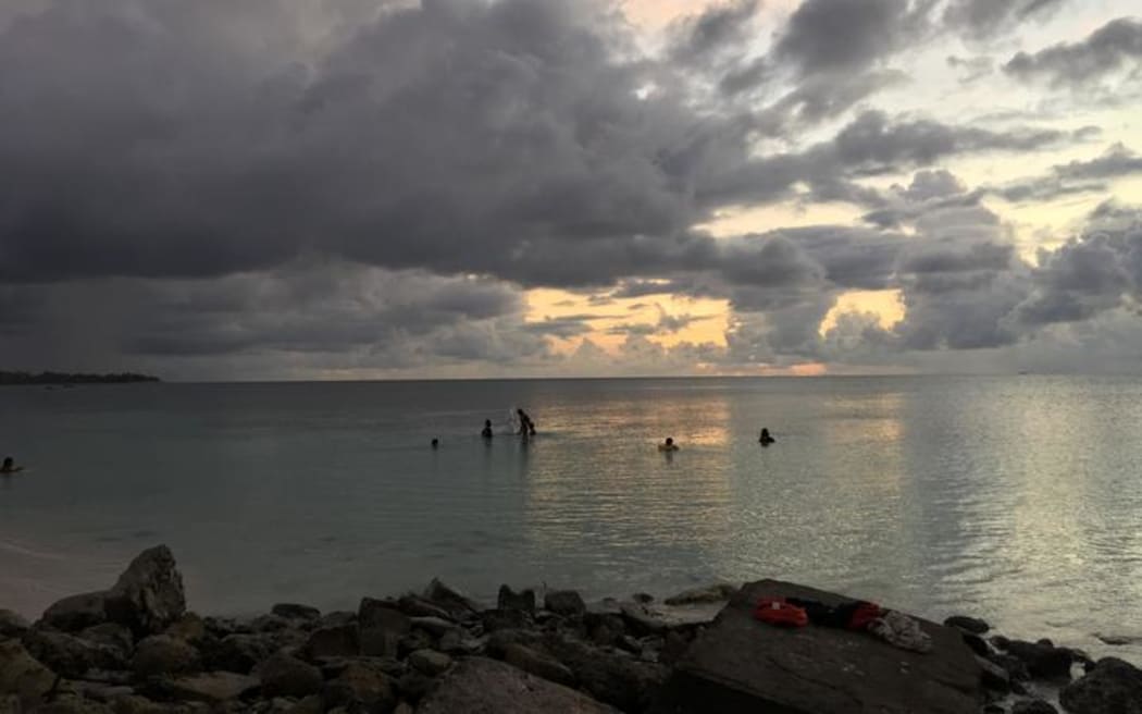 Funafuti lagoon, Tuvalu at sunset with a few  people in the water