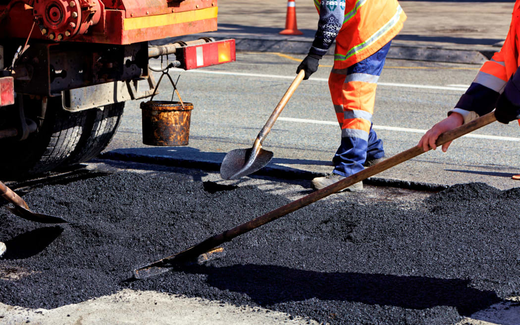 The road workers' working group renews a part of the road with fresh asphalt and levels it for repair in road construction.