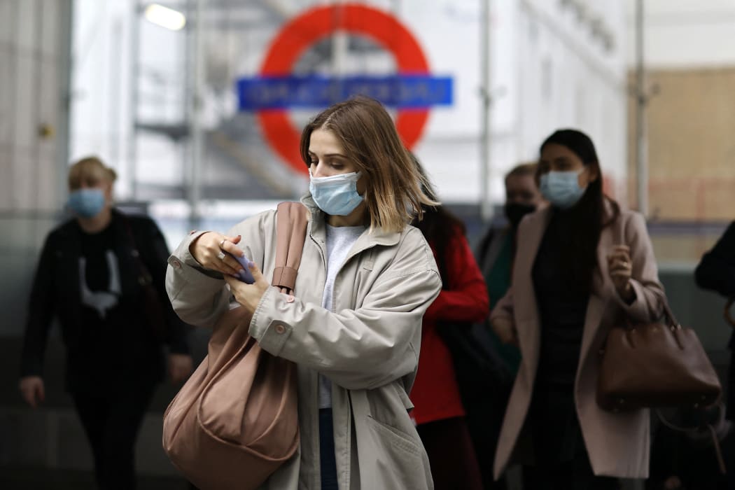 Commuters, some wearing face coverings to help prevent the spread of coronavirus, walk out of a Transport for London (TfL) underground train station.
