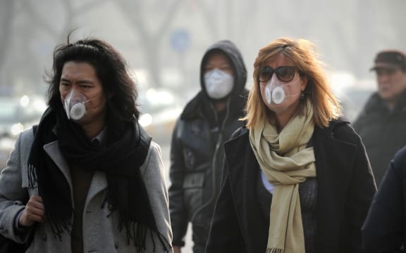 Pedestrians wearing face masks in a street in Beijing on 16 January.
