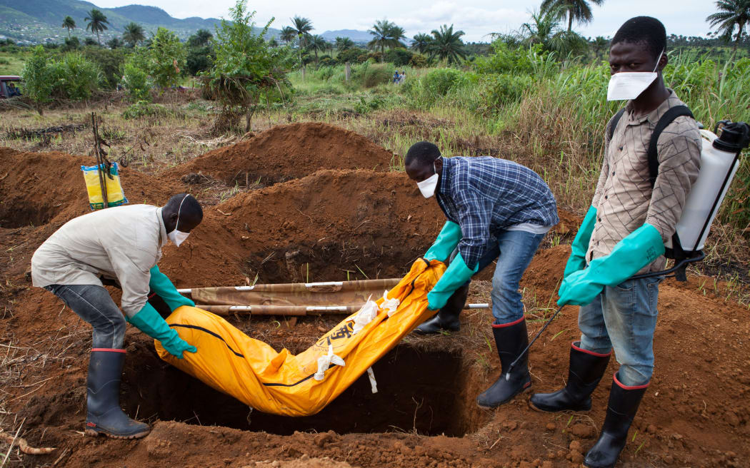 Volunteers in protective suits bury a person who died from Ebola in Sierra Leone.