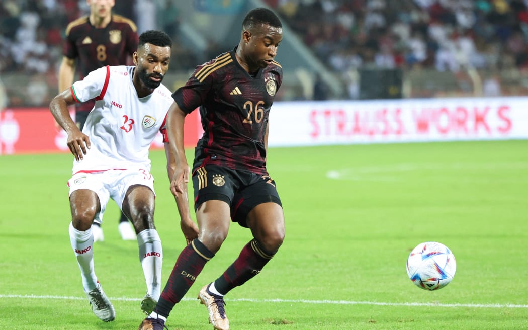Germany's Youssoufa Moukoko (r) fights for the ball against Oman's Harib Al-Saadi (r).