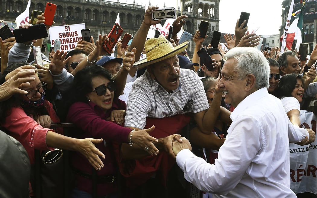 Mexican President Andres Manuel Lopez Obrador (R) greets supporters on arrival at the Zocalo square to commemorate his fourth year in office, in Mexico City, on November 27, 2022. (Photo by CLAUDIO CRUZ / AFP)