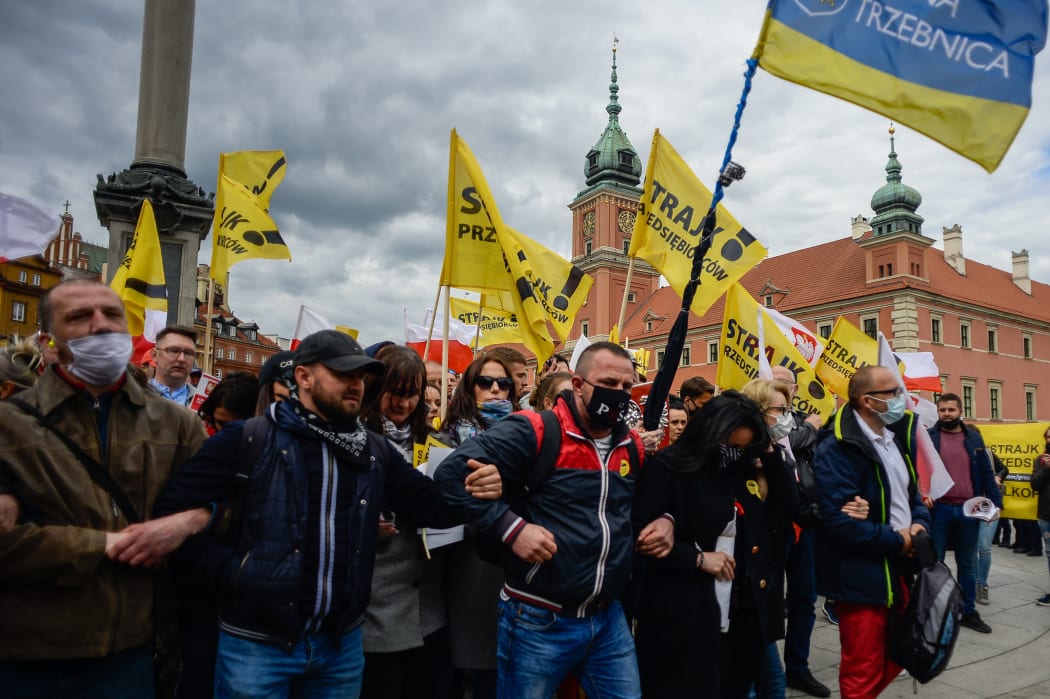People wear protective face masks as they take part in a protest against the Coronavirus economic package at the Castle Square in Warsaw, Poland
