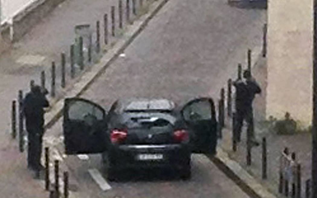 Armed gunmen face police officers near the offices of the French satirical newspaper Charlie Hebdo in Paris.