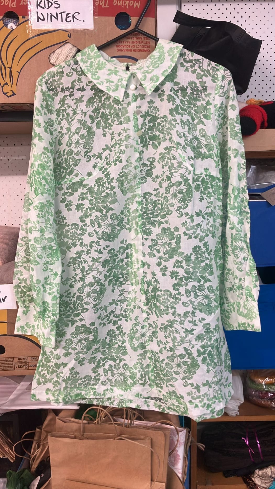 Picture shows a collared long sleeve dress with green floral patterns.