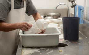 Man washing dish on sink at restaurant