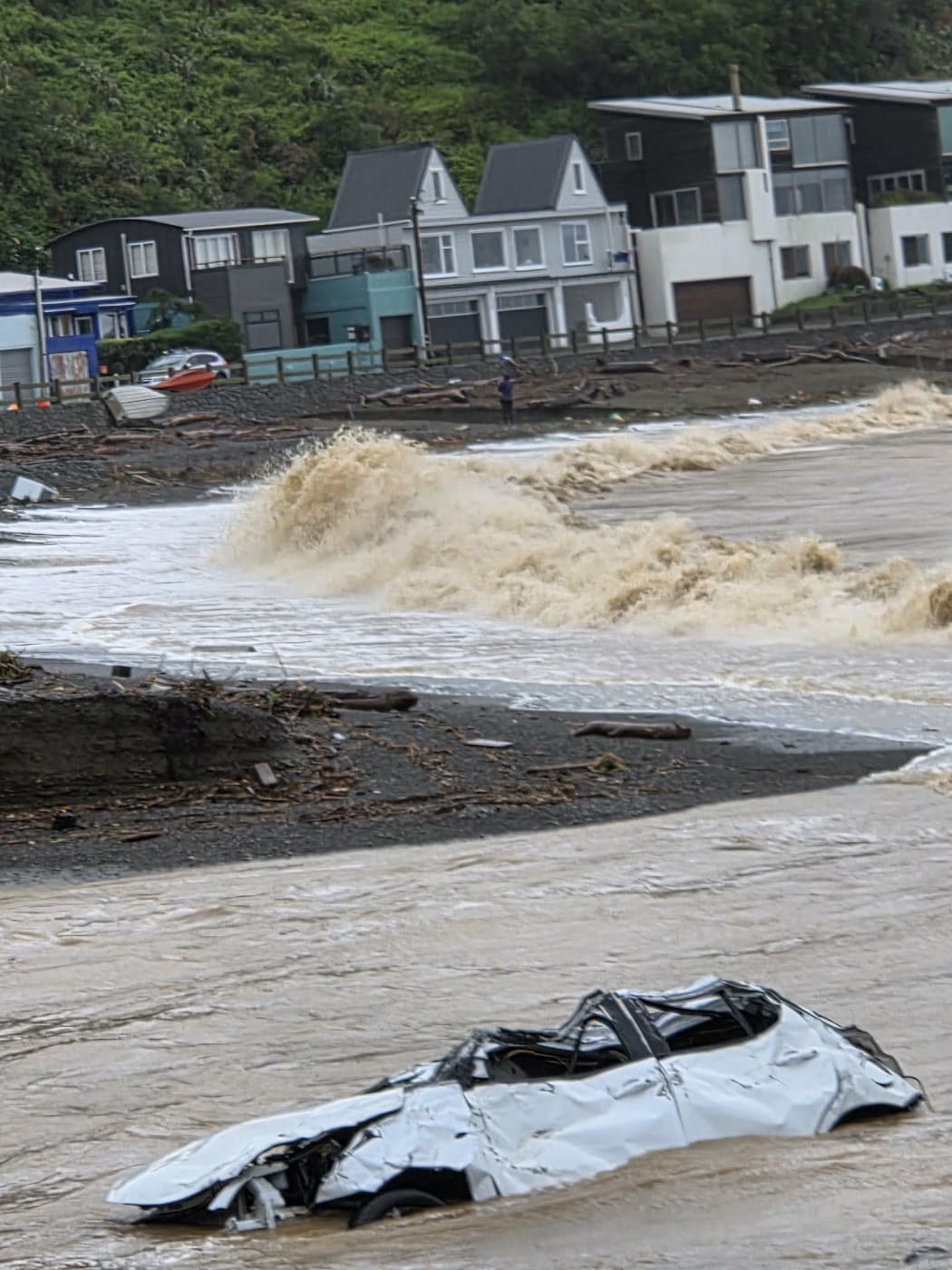 A car is submerged in the river mouth where the stream flows onto the beach in Ōwhiro Bay
