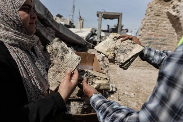 Archaeologist Hanin Al-Amassi and a colleague examine the brittle pages of a manuscript.